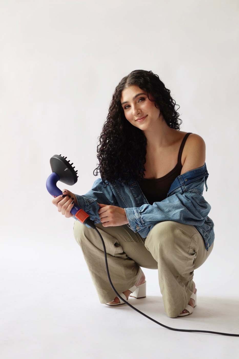 Sammy Feldman, curly hair educator, holding a hair diffuser
